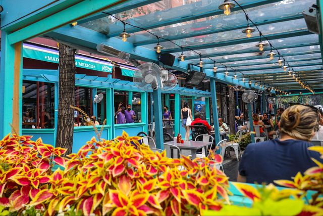 teal outdoor seating area with diners enjoying food